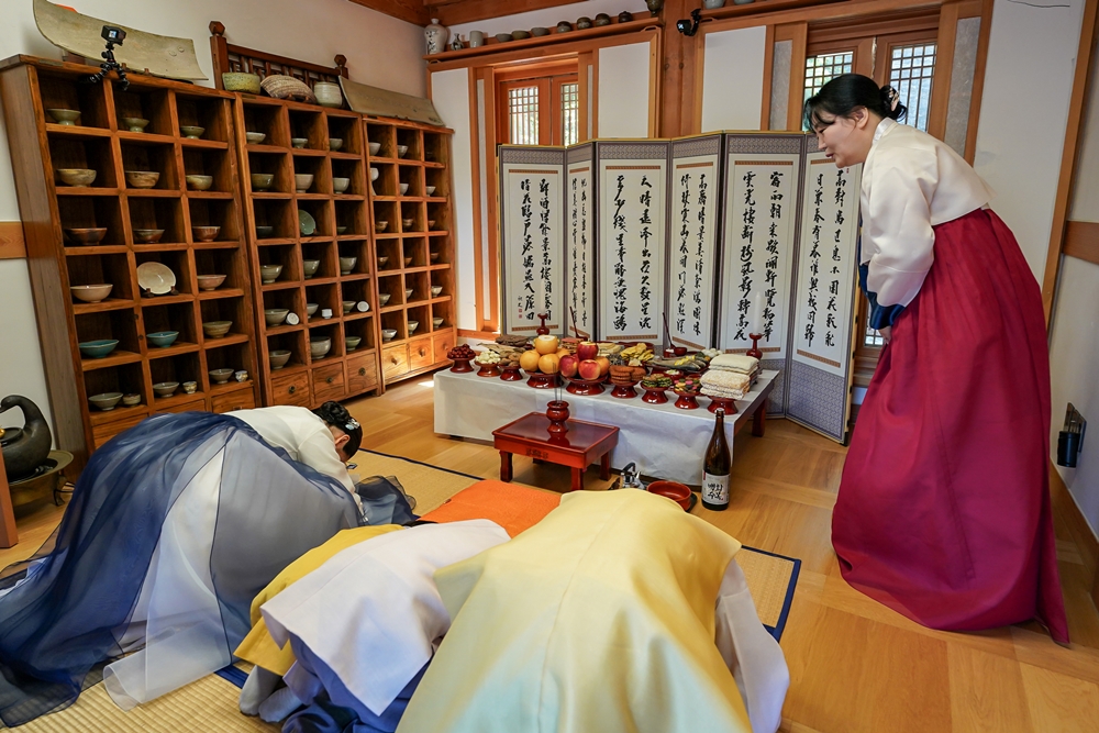 Cho Yoon-ju (right), chief of Korean Food Grand Master Center, on Sept. 22 last year introduces with models the traditional charye (ancestral rite) table and etiquette in a Chuseok demonstration hosted by the Korea Agro-Fisheries and Food Trade Corp. (aT) in Hanok Village of Seoul's Eunpyeong-gu District. (aT)  